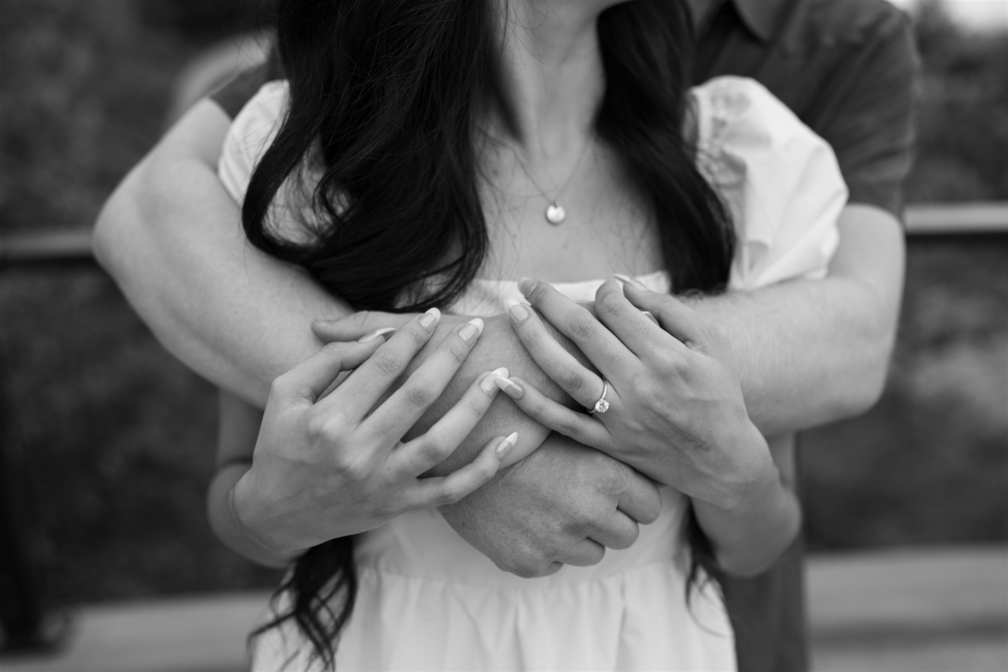 Couple holding hands with engagement ring visible at Gathering Place Tulsa park.