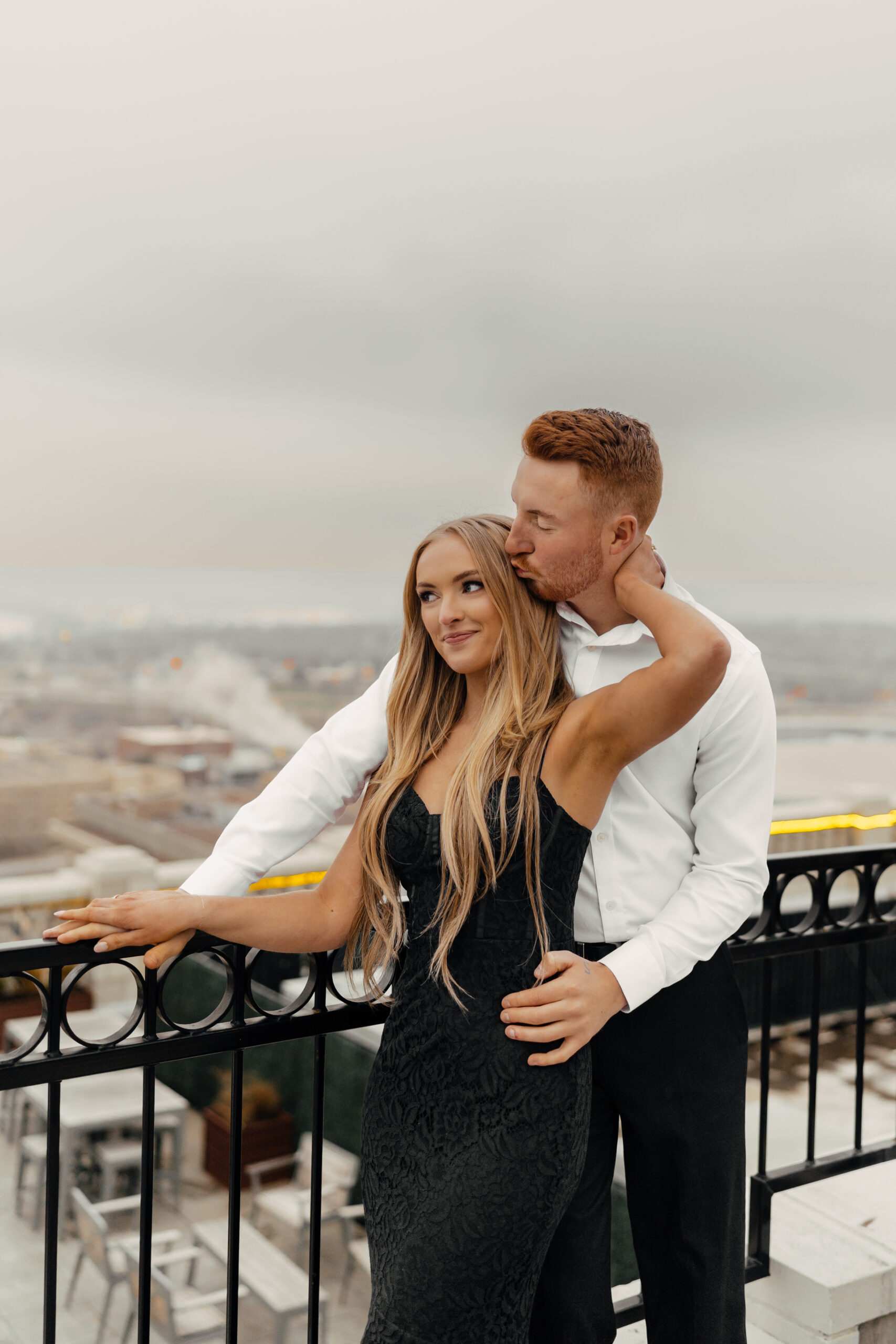 Rooftop engagement photo of couple holding hands in romantic golden light