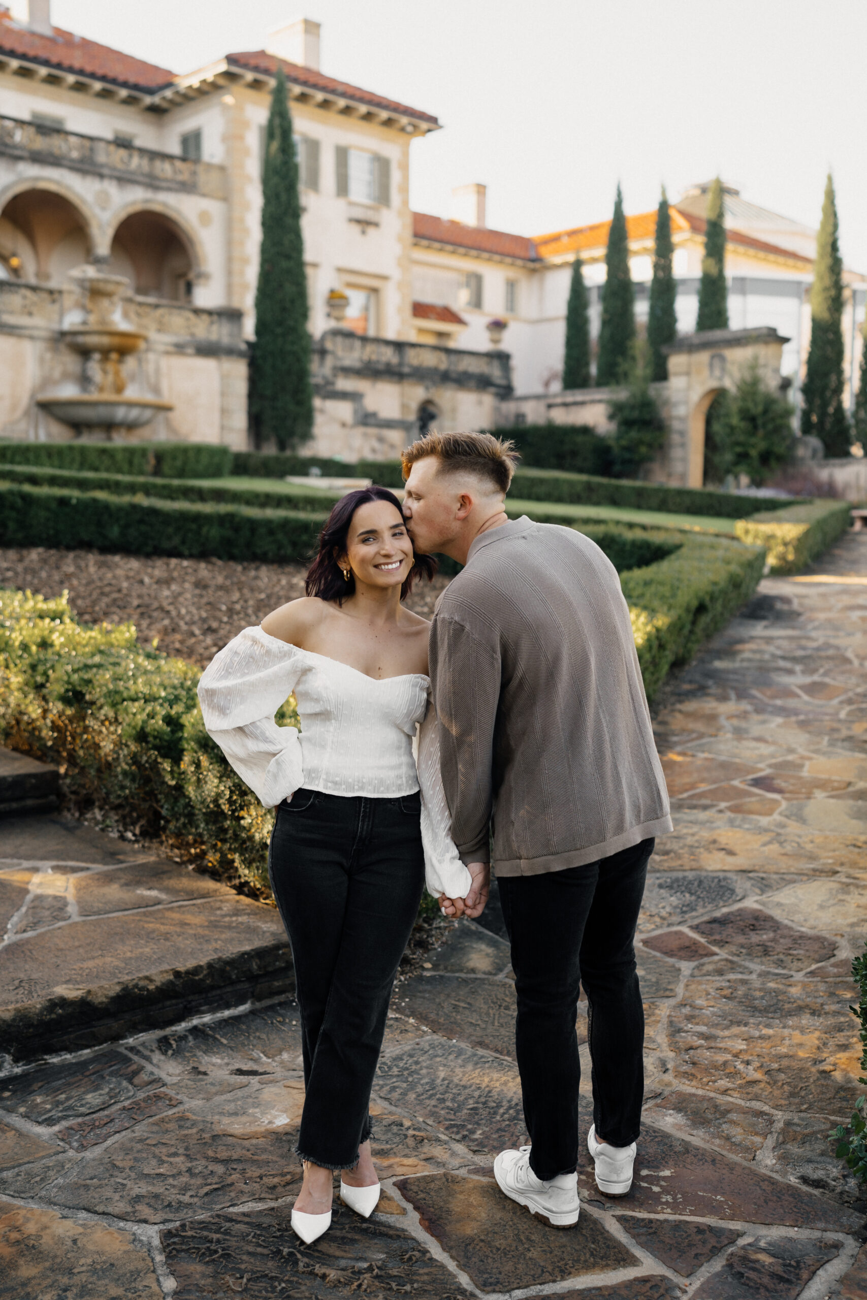 Couple holding hands in front of the historic Philbrook Museum architecture