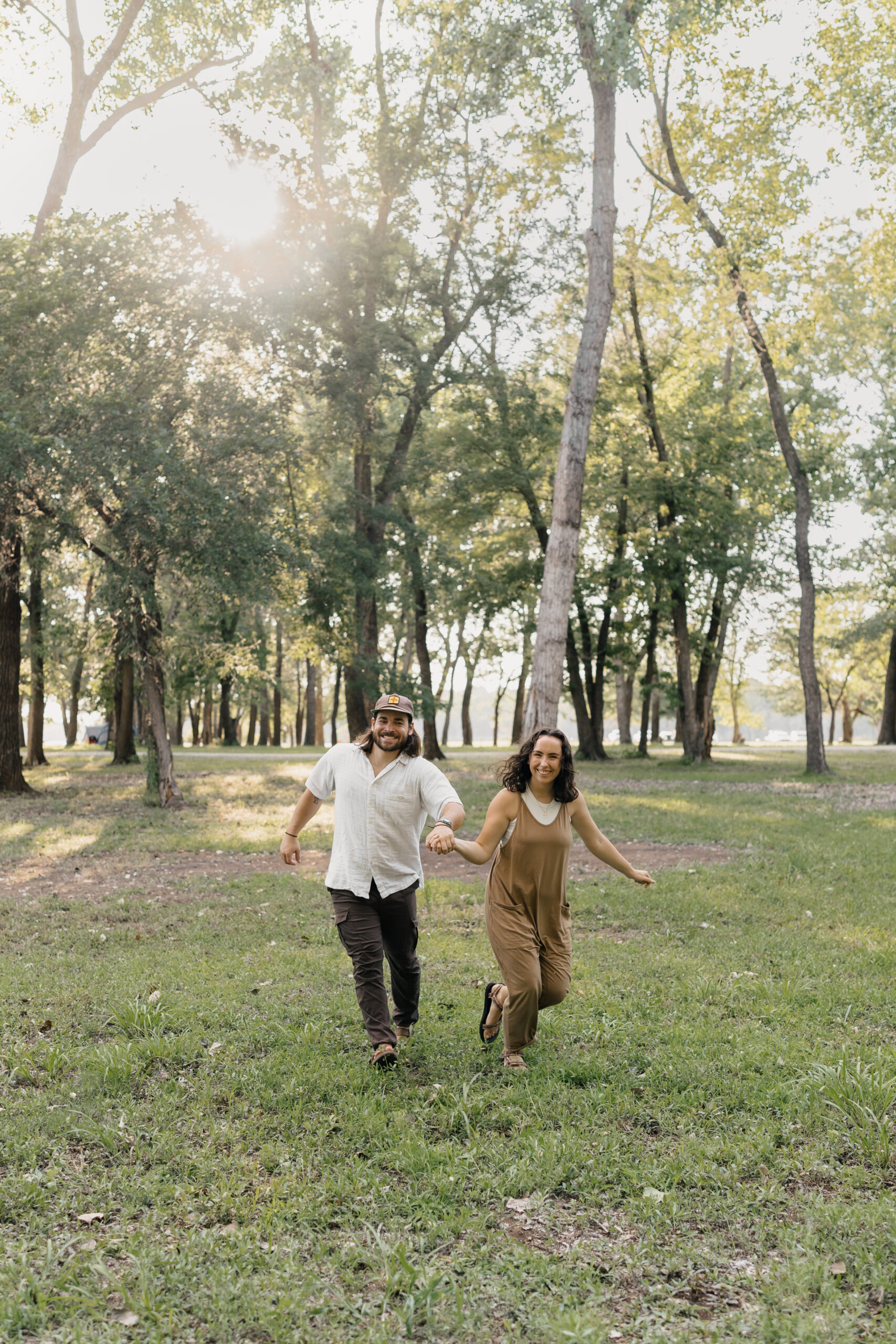 Engaged couple cuddling by the lake at golden hour during their Oklahoma engagement session