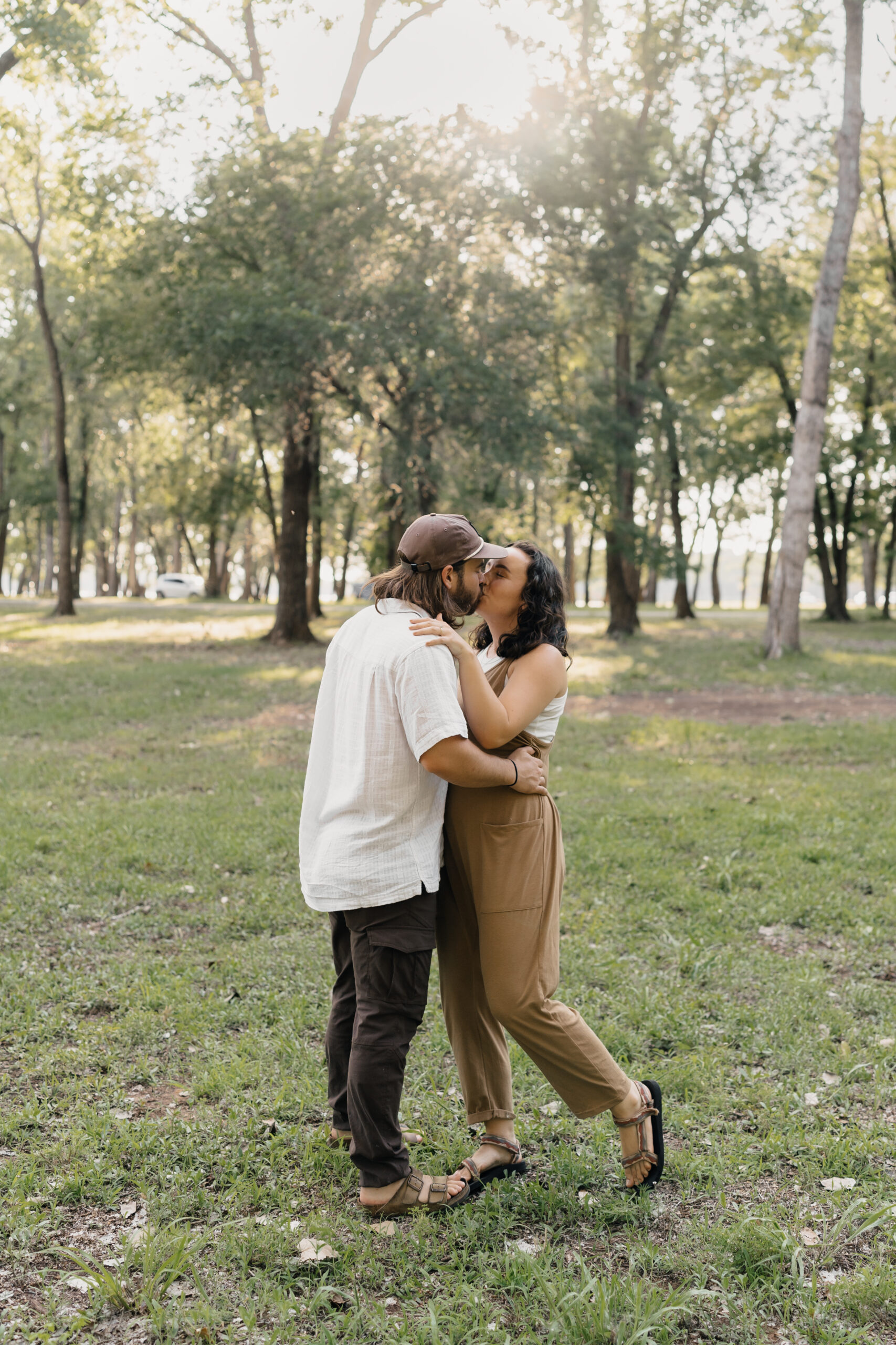 Engaged couple cuddling by the lake at golden hour during their Oklahoma engagement session