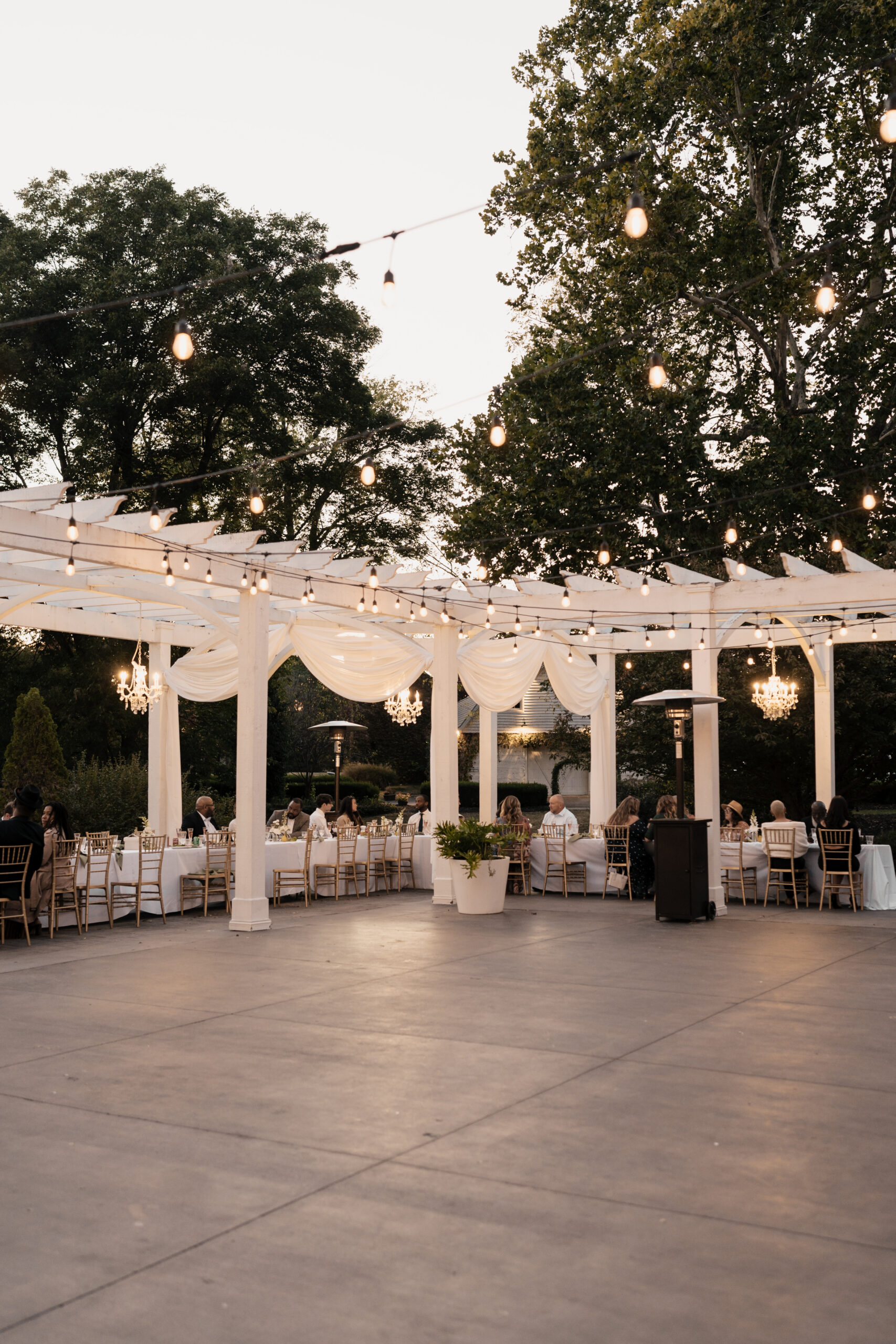 Outdoor reception under pergola chandeliers