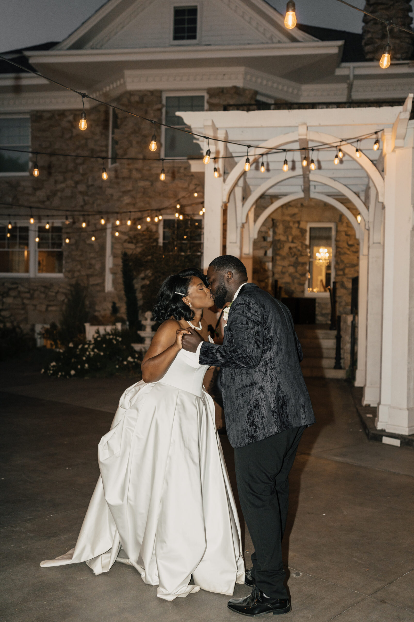 Couple sharing first dance in courtyard with romantic Tuscan lighting