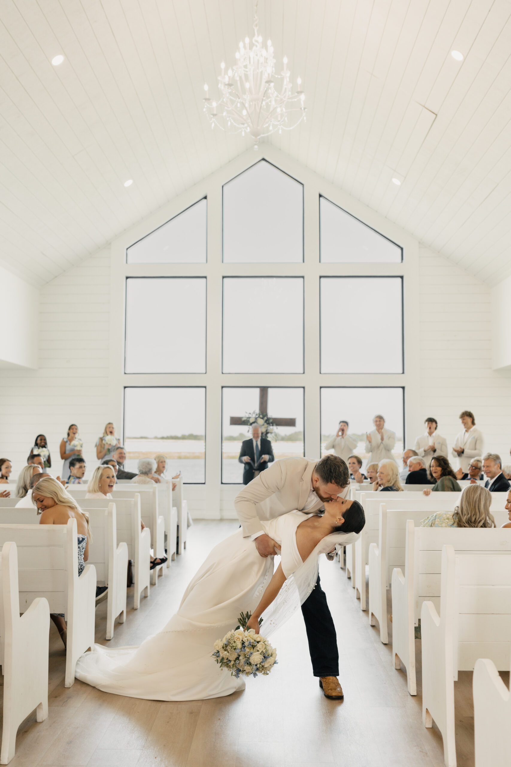 Indoor ceremony setup at The Gardenia in Valley View, Texas, surrounded by greenery and elegant white pews.
