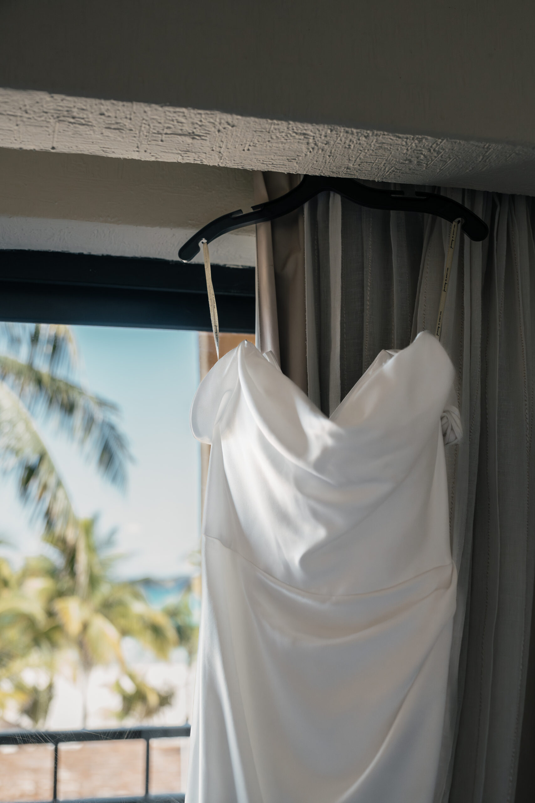 Wedding dress hanging in tropical resort suite