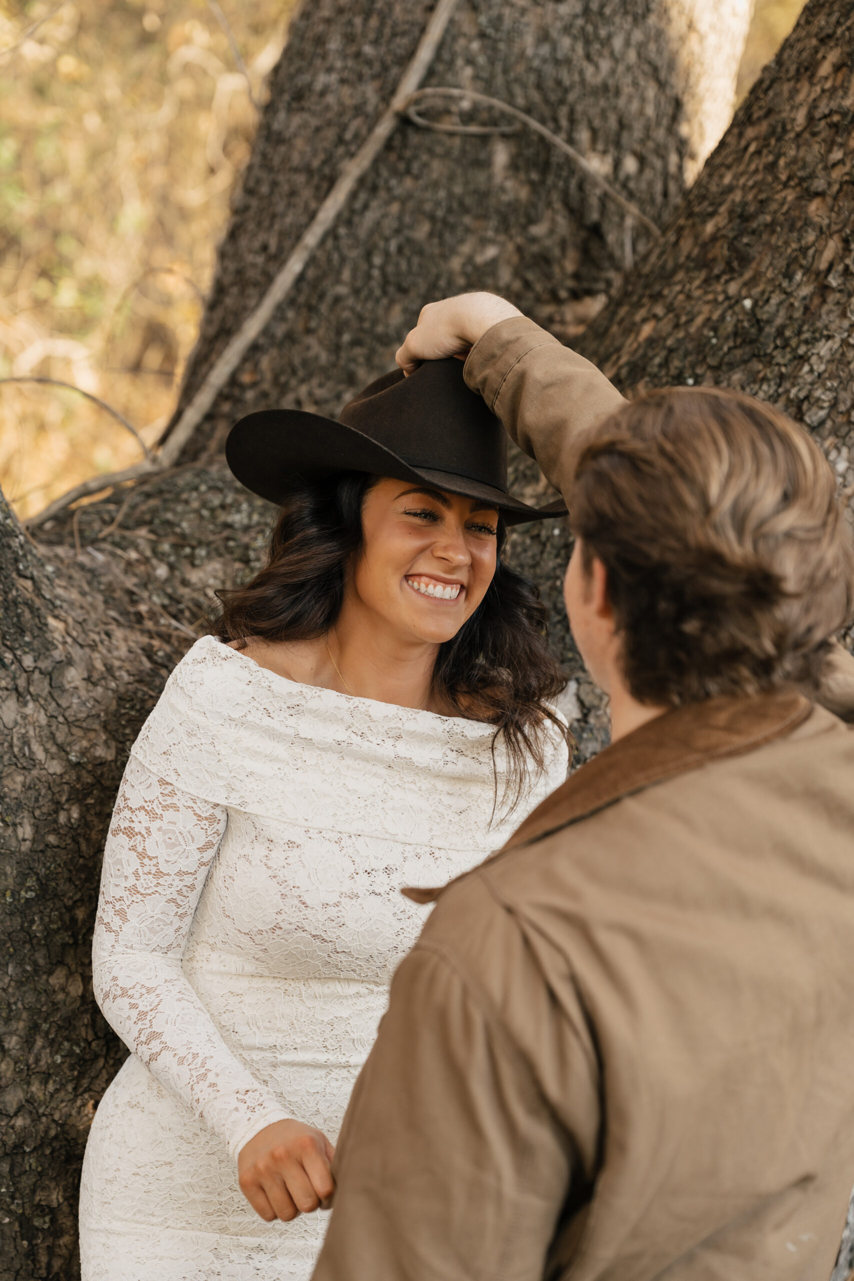 Bride-to-be laughing while wearing boots and a hat in a rustic country setting