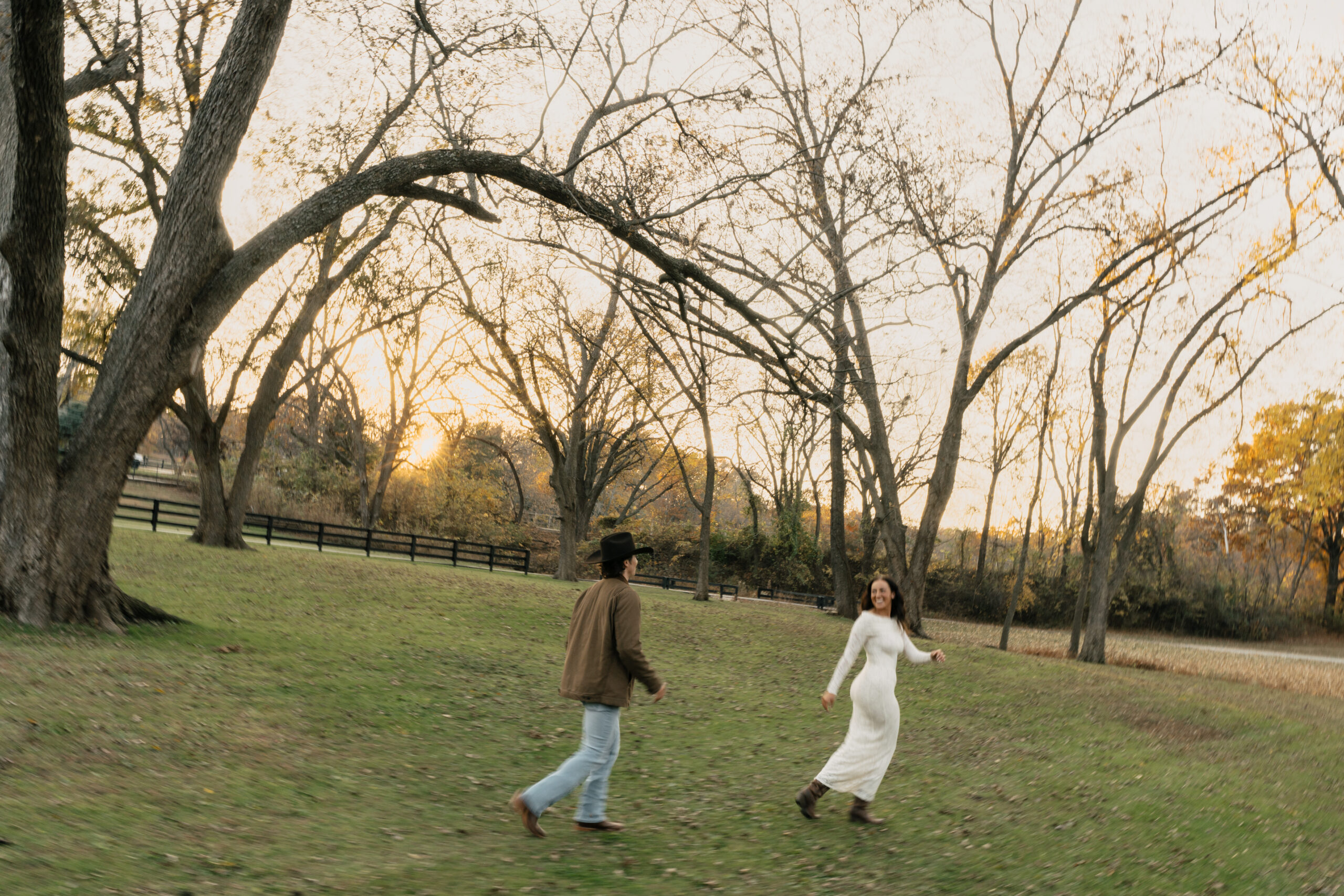Couple embracing while running through Spain Ranch fields at sunset